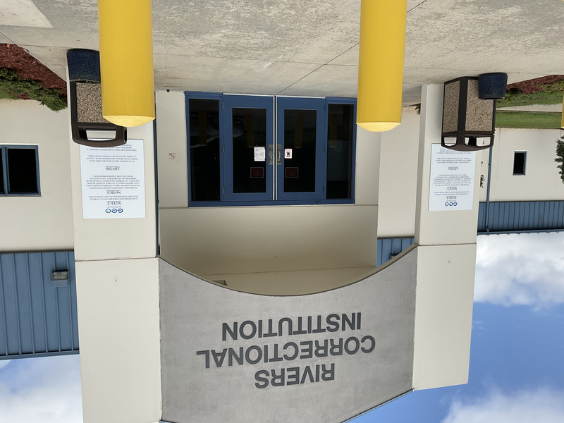 Front entrance to Rivers Correctional Institution, a navy blue and gray concrete prison building in unincorporated Hertford County, North Carolina