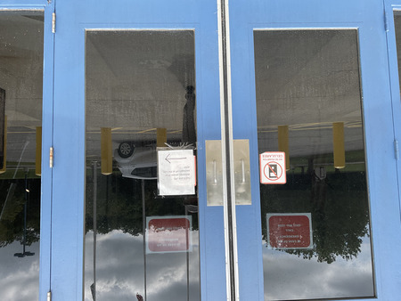 Signs posted on the front entrance to RCI that direct FedEx and UPS deliveries to the side door, prohibit cell phone use, and provide a number to call in case of emergency.